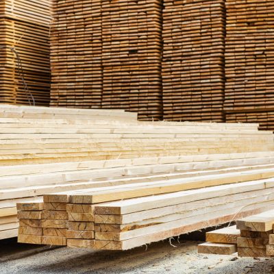 A lot of boards stacked on top of each other in a lumber yard. Wooden boards in the foreground close-up.
